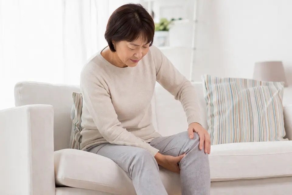 ソファで膝を押さえる女性